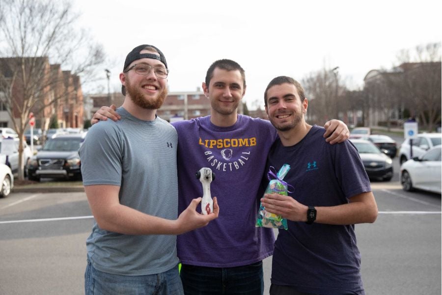 three students holding up their derby cars from music city best competition