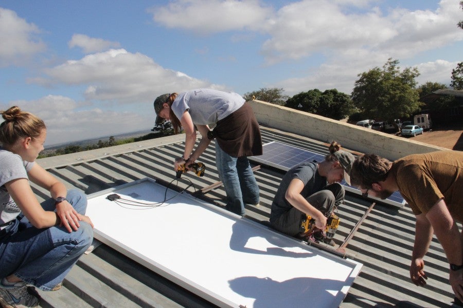 Students work to install solar panels in Malawi in 2019