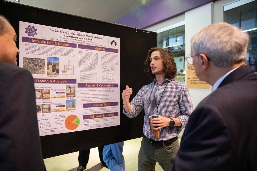 Reid Murdock presents his poster at the symposium.