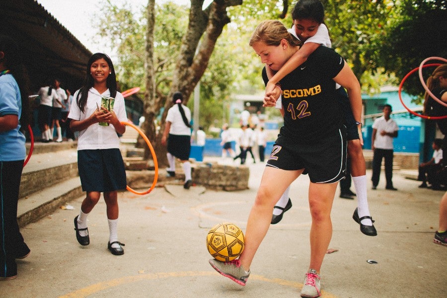 Student athletes playing soccer with children in El Salvador