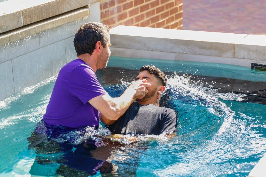 Athletics Spiritual Formation Director baptizing a student athlete in the on-campus fountain