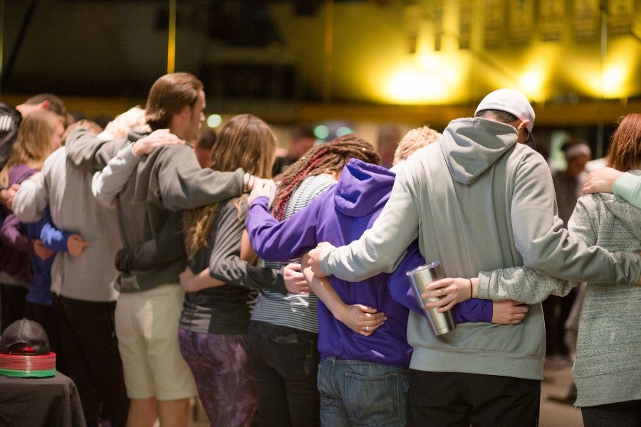 Student Athletes linked arm-in-arm praying