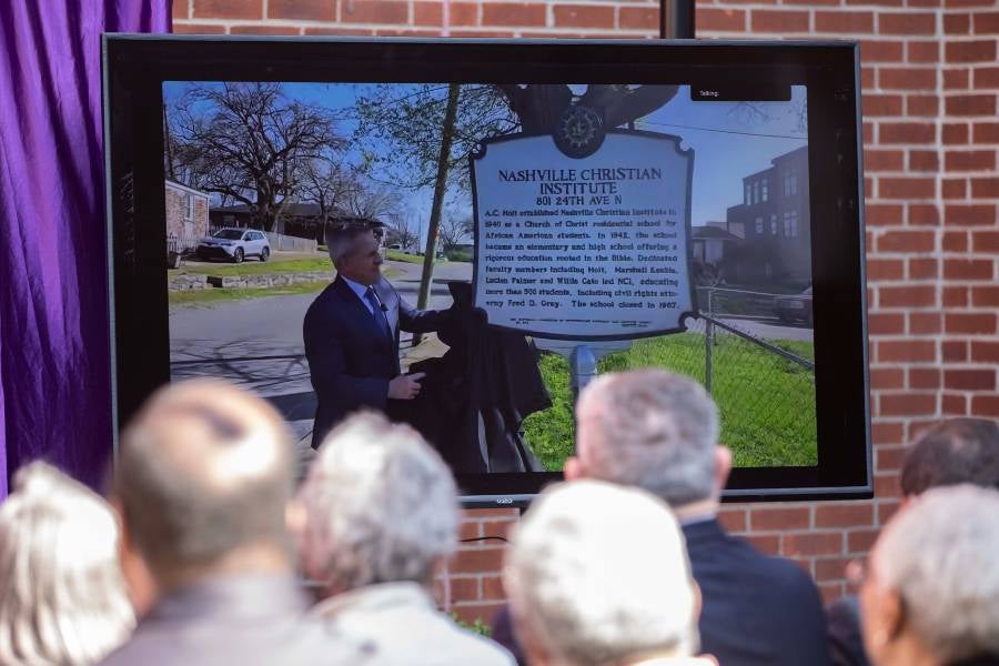 The video screen showing the 24th Ave. N. city historical marker at the on-campus ceremony