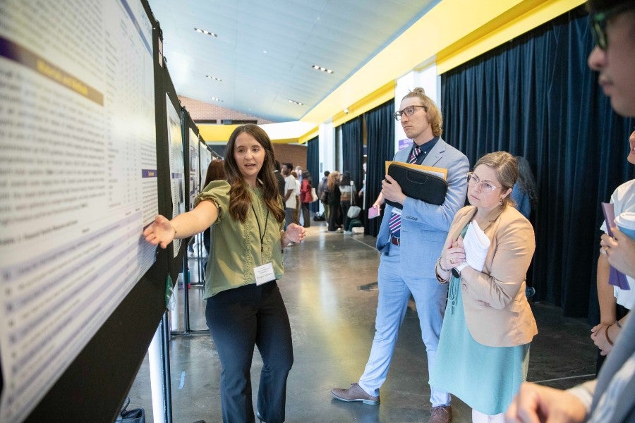A students presenting her research poster at the symposium