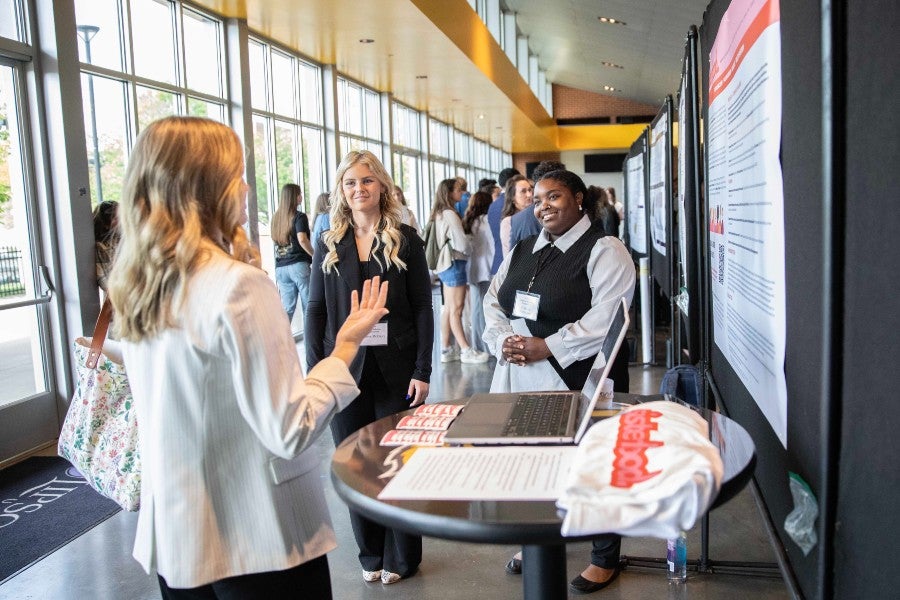 Communication student and attendees converse at the Student Scholars Symposium