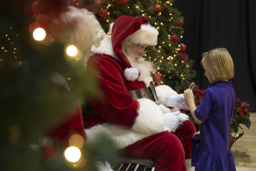 child getting candy cane from santa