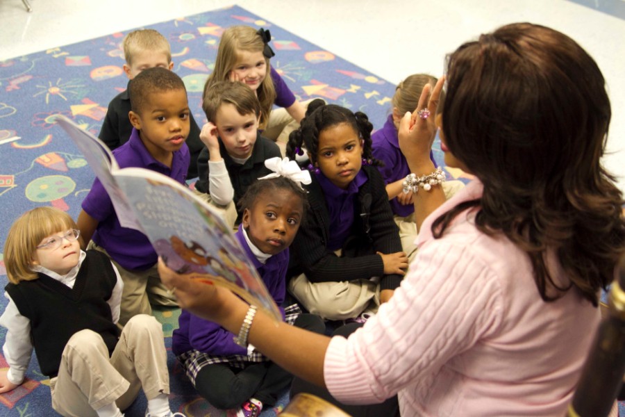 Teacher reads book to group of elementary school children. 