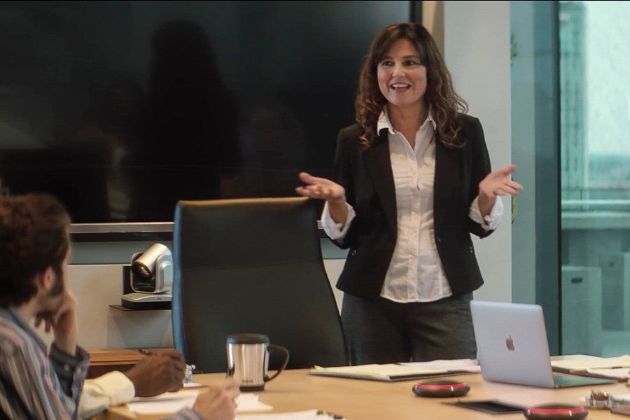 Woman in business setting standing and leading a discussion. 