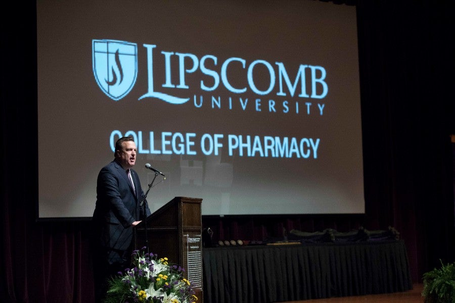 Male faculty member standing at podium in front of screen that has Lipscomb logo.