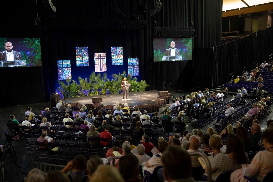 Auditorium filled with people singing and worship leader on the stage