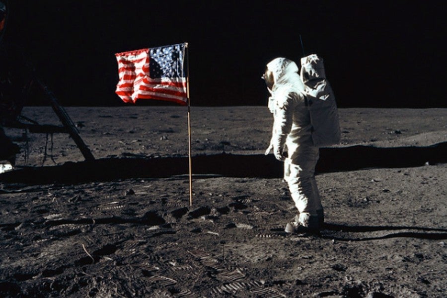 Neil Armstrong standing on moon near US flag. 