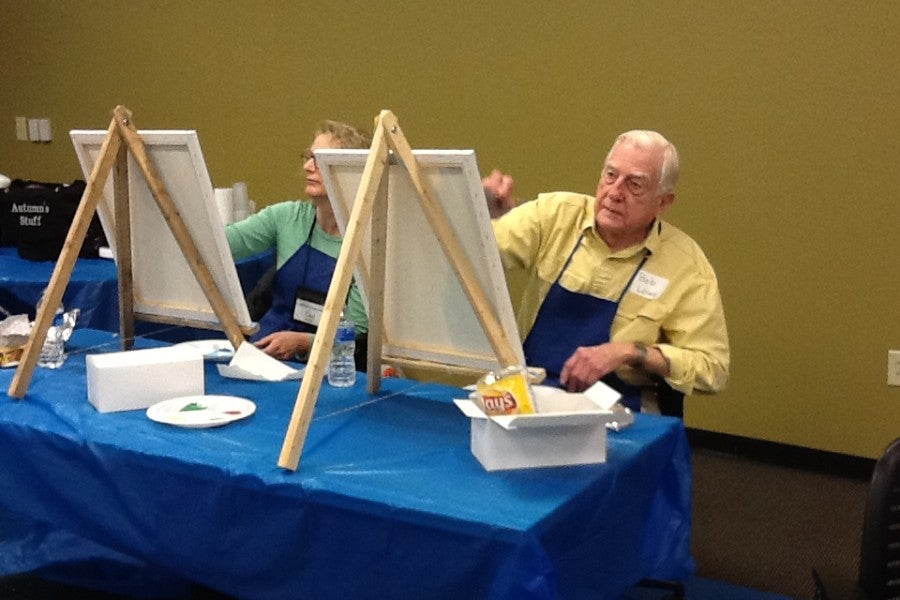 Older gentleman painting at an easel