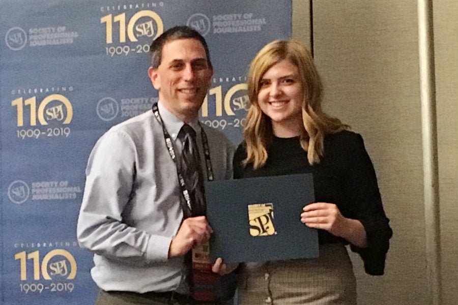 Two people standing with award