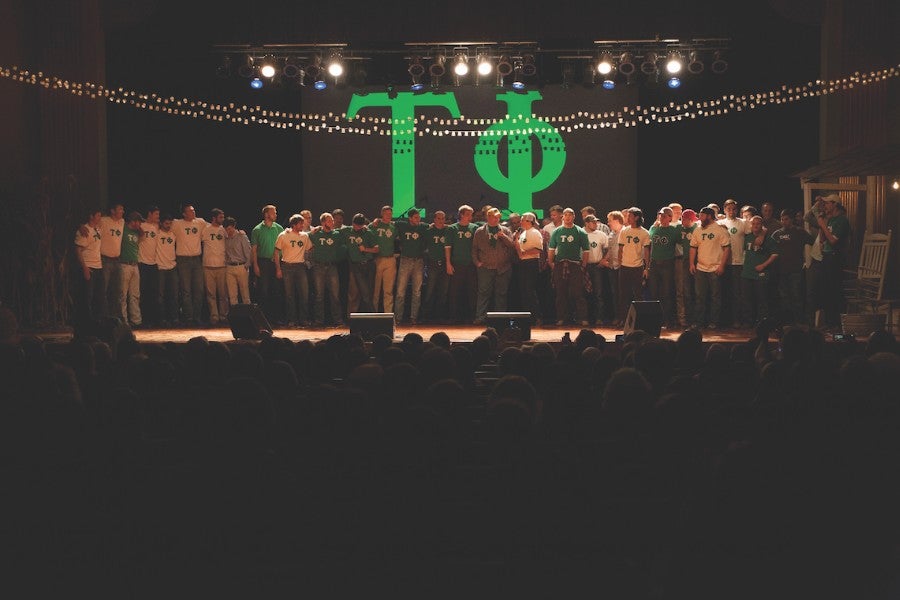 Group of male students standing on the stage of Collins Auditorium.