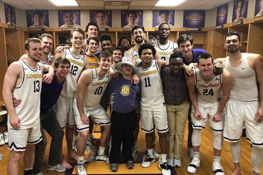 Bison men's basketball team in lockerrroom standing with Conner.