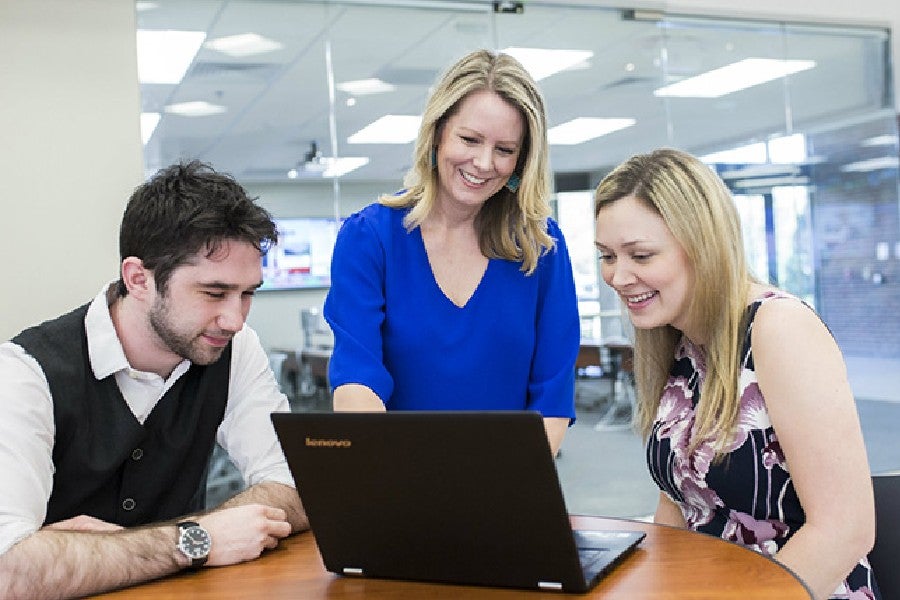 Business professor and two students looking at computer screen