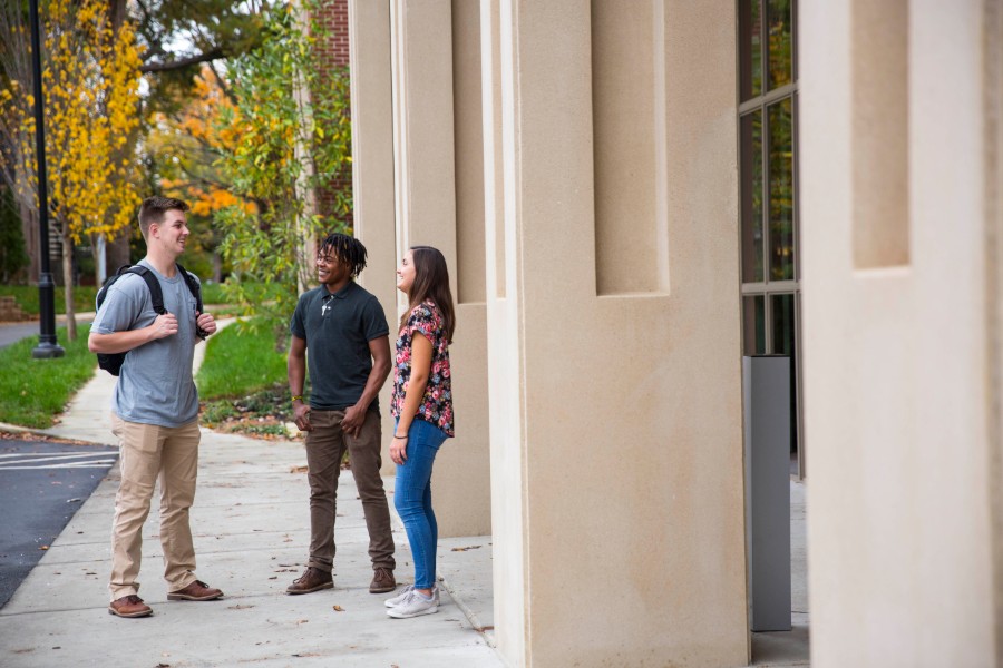 Three students standing in front of a building on the Lipscomb campus.