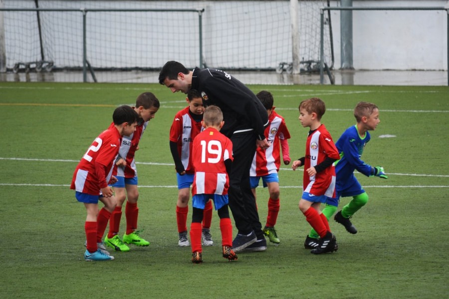 Soccer coach surrounded by group of young players