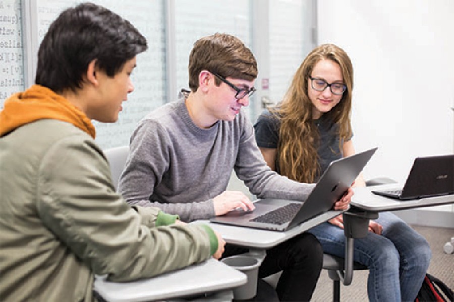 Three students gathered around a computer