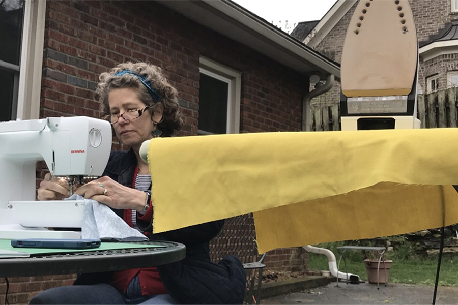 June Kingsbury sewing outside by an ironing board