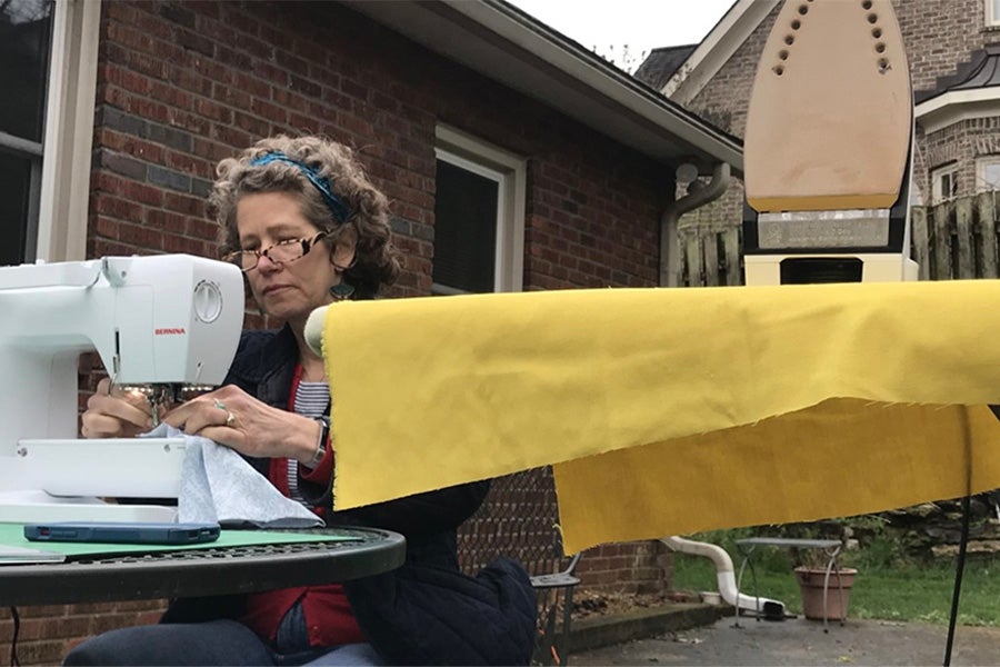 June Kingsbury sewing outside by an ironing board