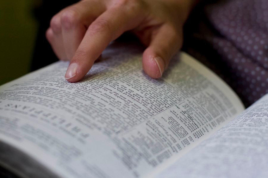 Photo of an open Bible with a hand pointing to a scripture