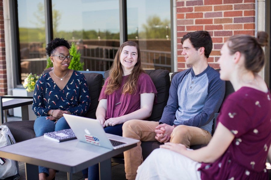 Four students sitting outside looking at a computer