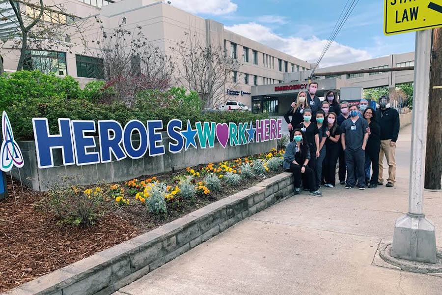 Health care workers posing by a sign saying "Heroes work here."