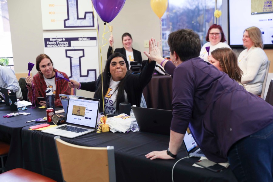 Lipscomb day of giving, people high five behind a lap top to celebrate