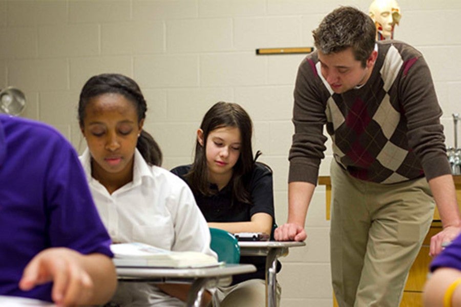 Teacher in classroom assisting student