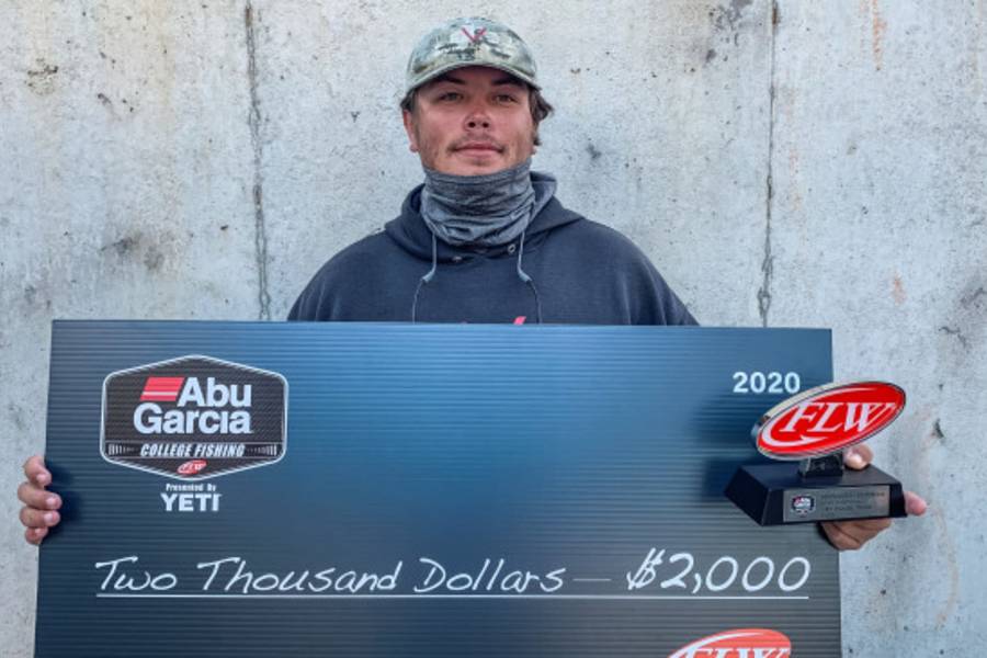 Photo of student holding check for winning fishing tournament. 
