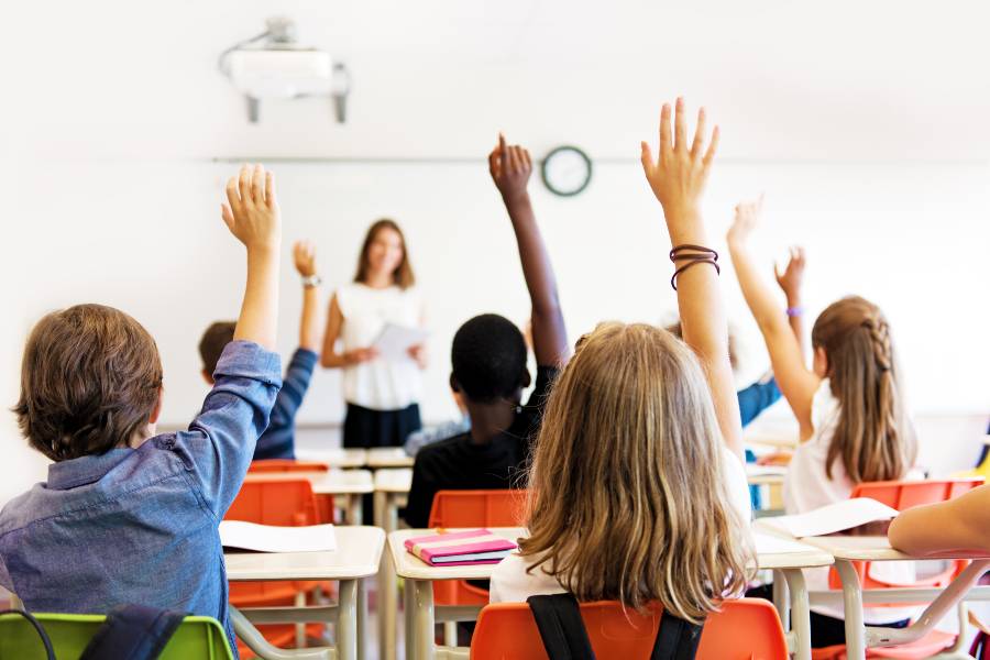 Students raising their hands in classroom setting