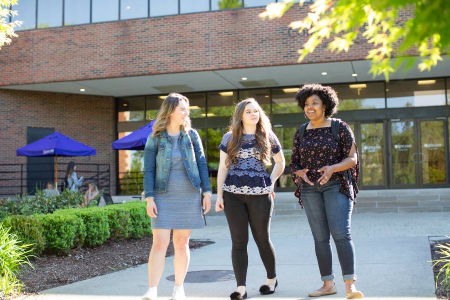 Three students walking in front of Swang