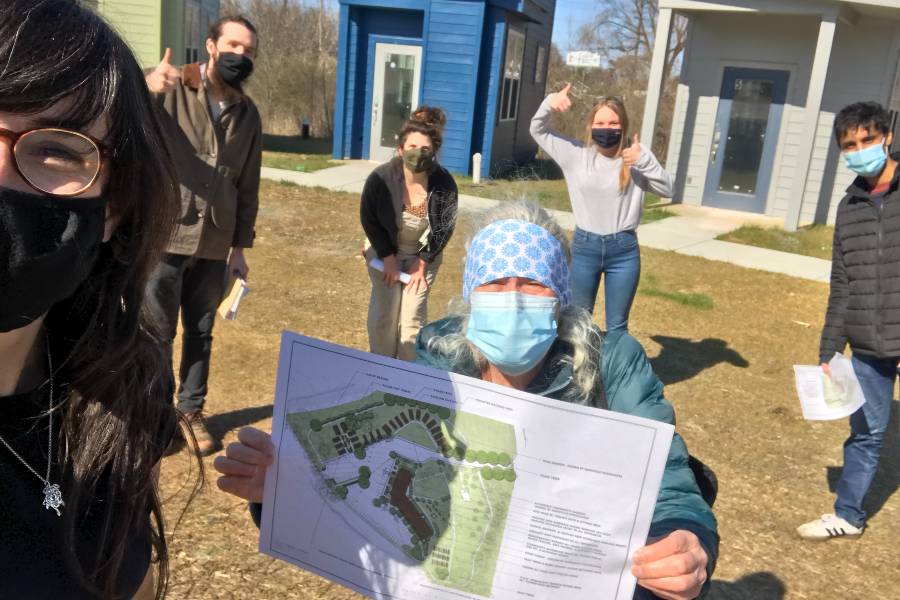 Volunteers holding master plan for The Village and garden. 