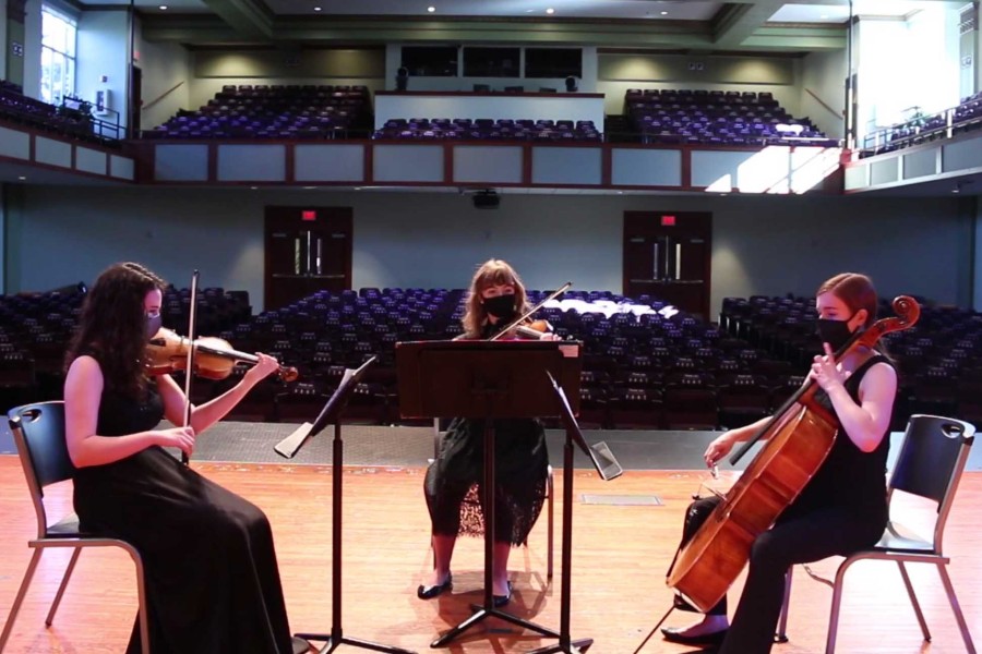Student music trio performing to an empty auditorium with masks on
