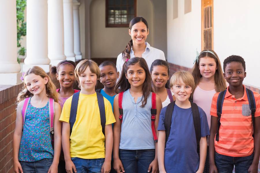 Group of children standing with an elementary school teacher.