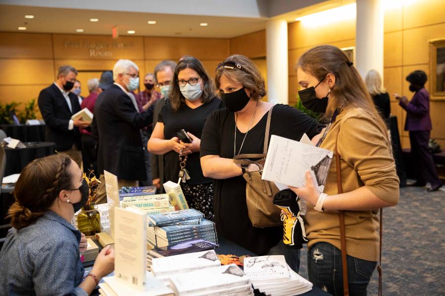 Guests at the faculty signing event purchase books. 