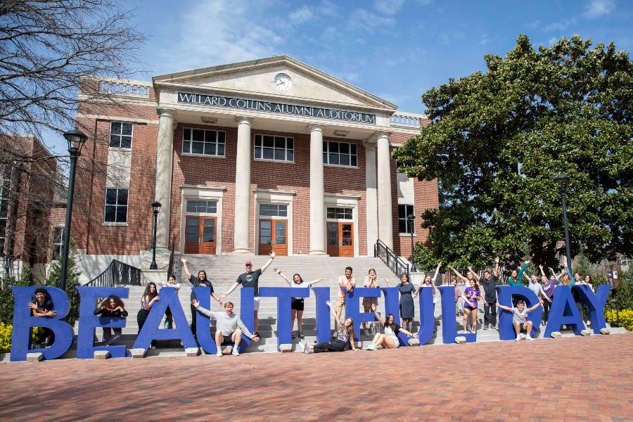 Students in front of Collins and Beautiful Day sign. 