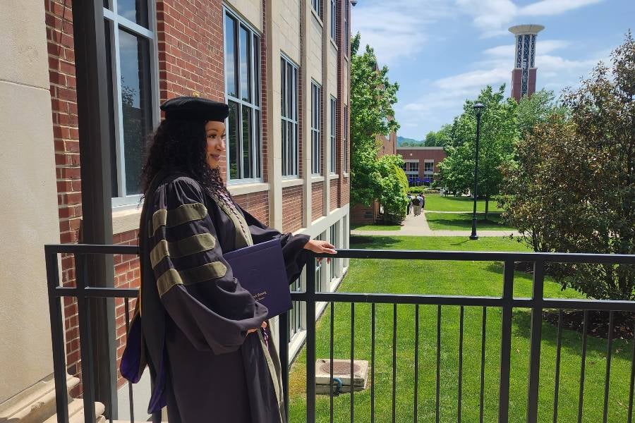 Christine Hunter dressed in regalia standing outside of the College of Pharmacy