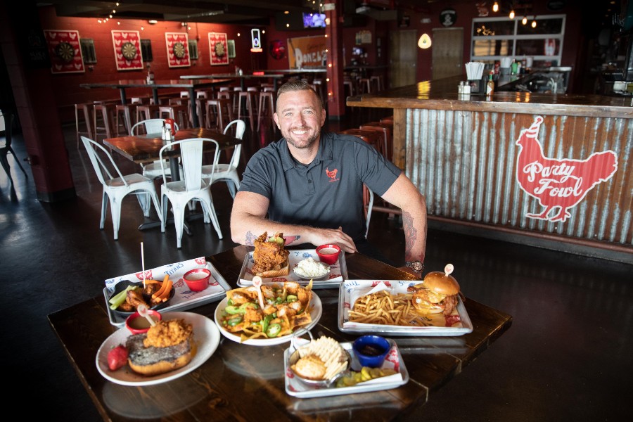 Austin Smith seated at table covered with popular menu items at Party Fowl’s Donelson location