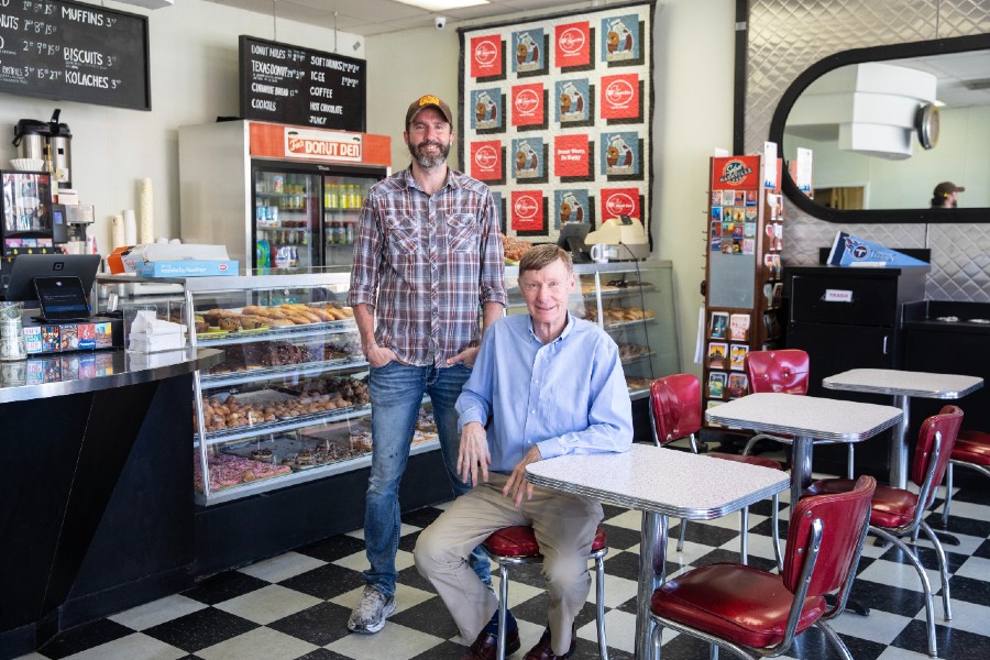 Ted stands next to his father Norman Fox (seated) inside the Donut Den.