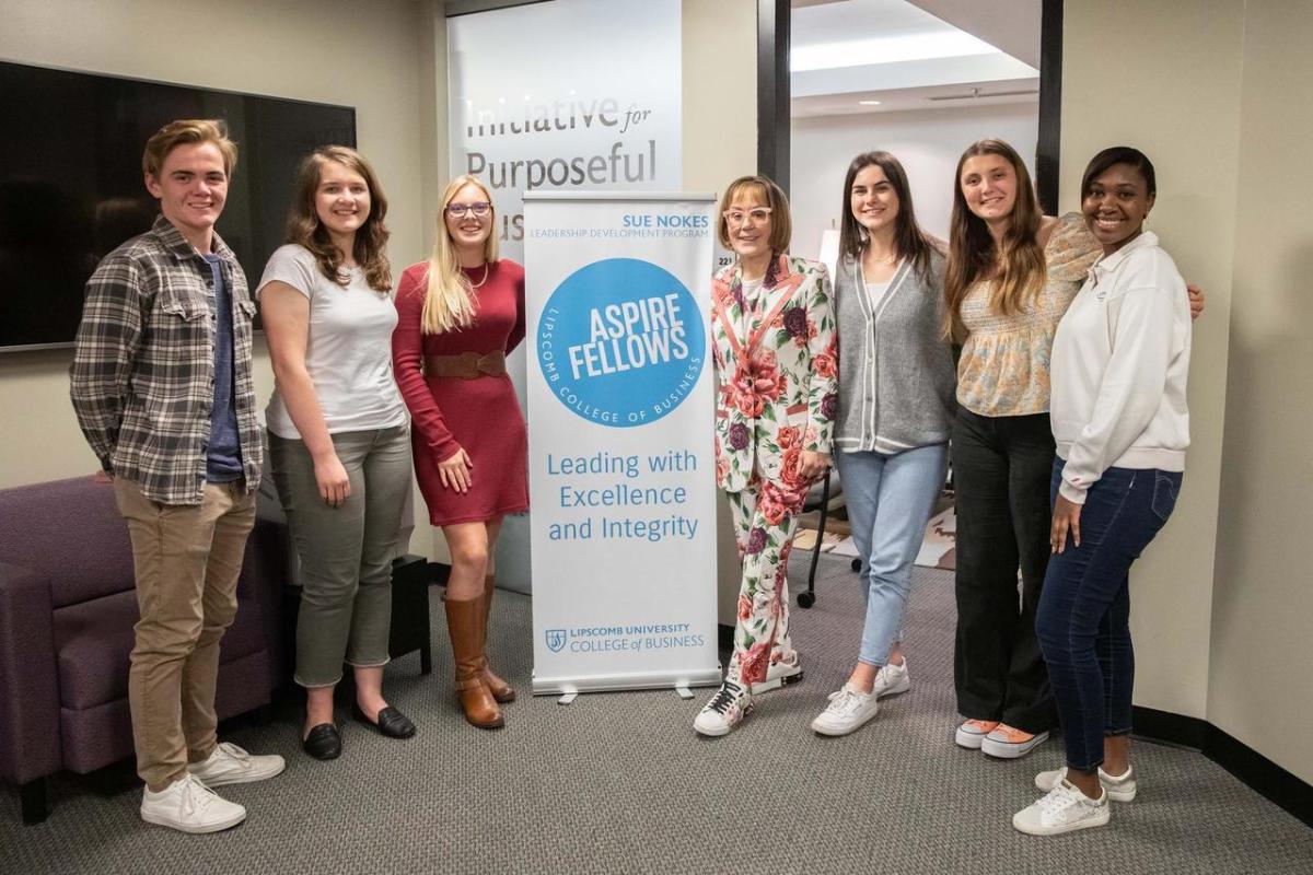 Business students standingaround Sue Nokes and banner identifying the new program.