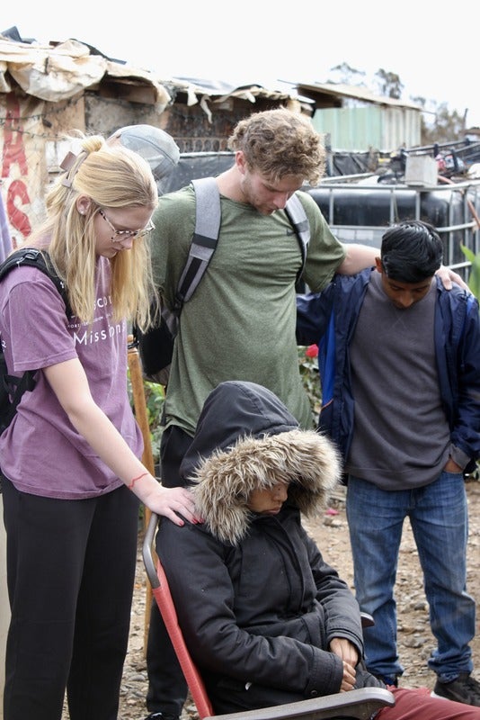 Baja members pray over community members.