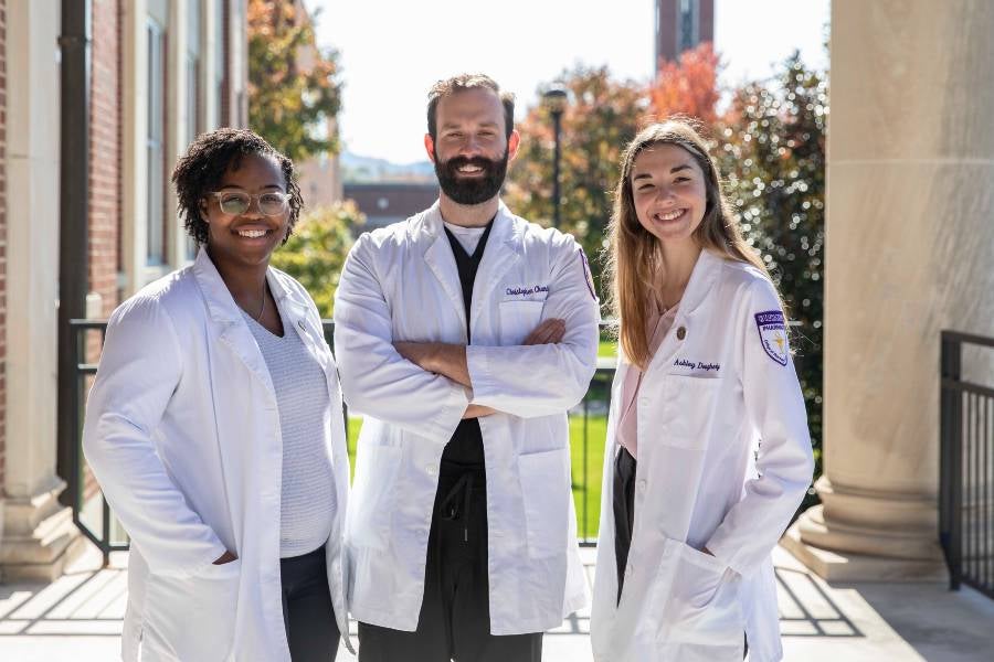 Three pharmacy students standing on the steps of Burton Health Sciences Building.