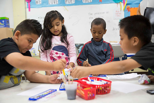 A group of children of minority populations play with crafts at a table