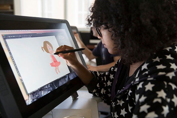 A female student draws a young brunette ballerina character on a tablet