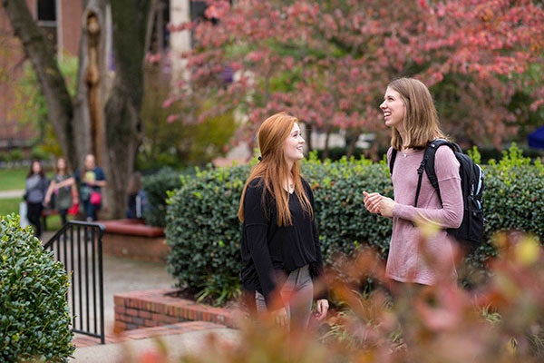 Two students stand outside talking