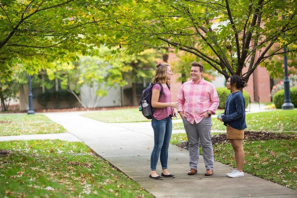 3 students stand outside talking