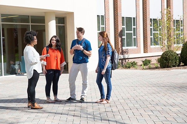 Four students standing outside and talking