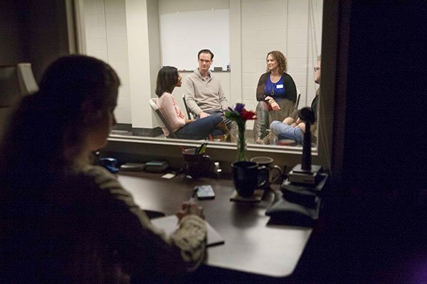 A student observes from a separate room discussion between patients and a psychologists